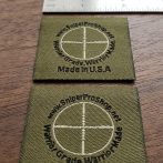 close-up photograph of woven labels showing micro-text with ruler showing scale, demonstrating legibility of small text
