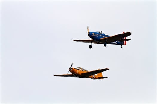 Two vintage propeller planes flying in formation against a clear sky.