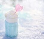Warm beverage topped with cream in snow, perfect for winter themes.