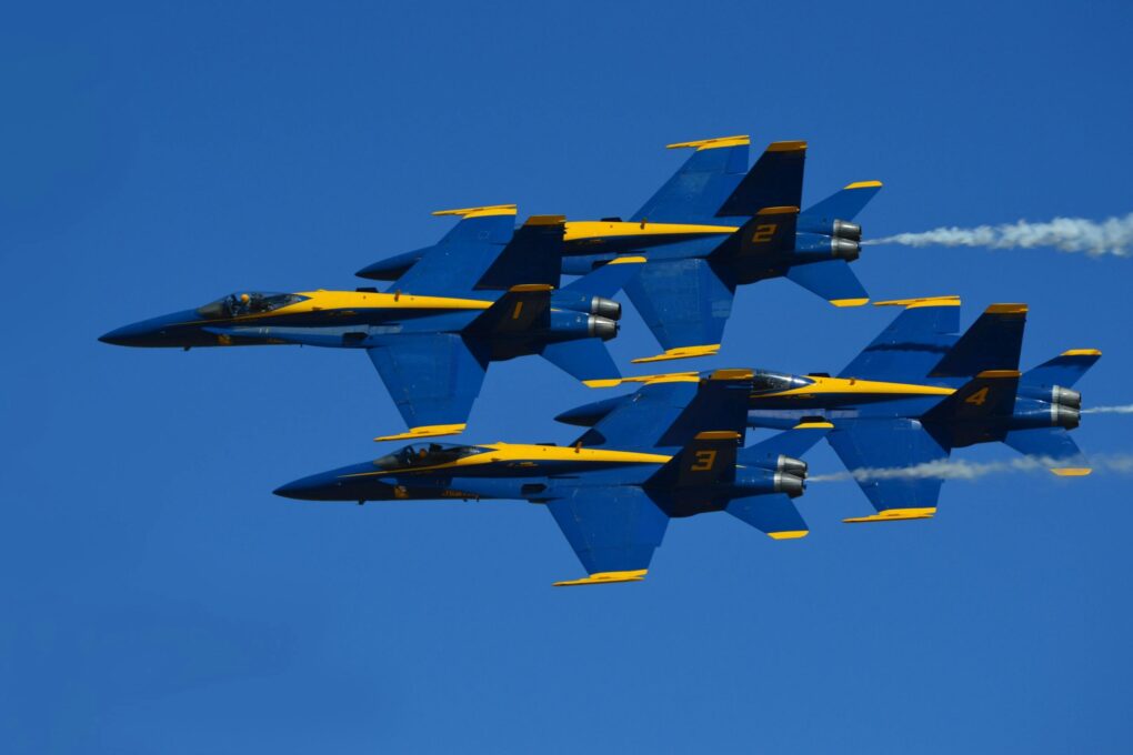 pexels-photo-3758435-3758435 Four Blue Angels jets performing an aerobatic maneuver set against a clear blue sky.