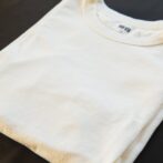 pexels-photo-5746087-5746087 A folded white t-shirt placed on a dark surface, showcasing minimalist fashion.