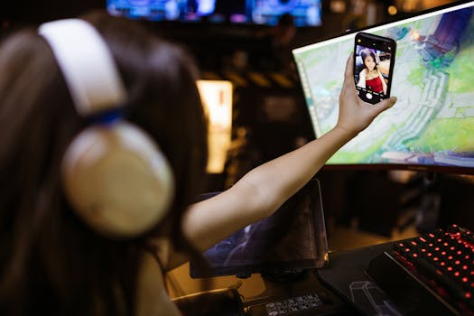 A woman wearing headphones takes a selfie with her smartphone while engaged in gaming indoors.